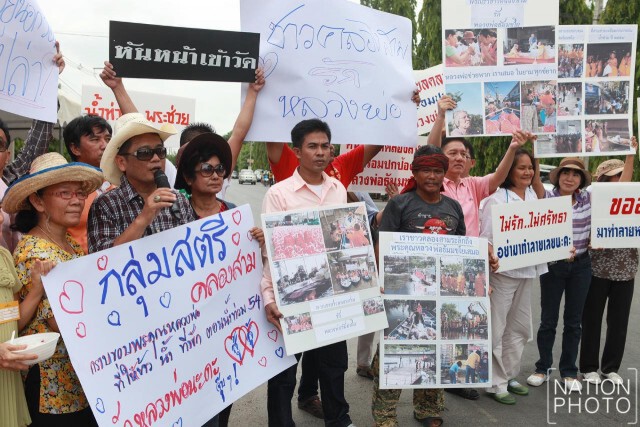 ชาวบ้านคลองสามที่สนับสนุนวัดธรรมกาย ถือป้ายให้กำลังใจ "ธัมมชโย"