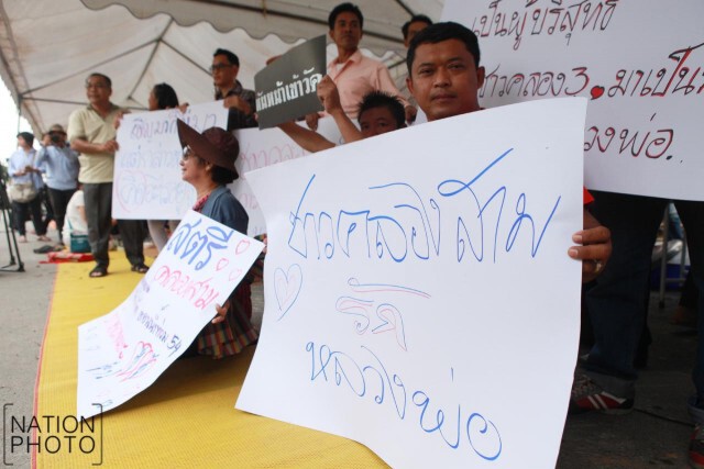 ชาวบ้านคลองสามที่สนับสนุนวัดธรรมกาย ถือป้ายให้กำลังใจ "ธัมมชโย"
