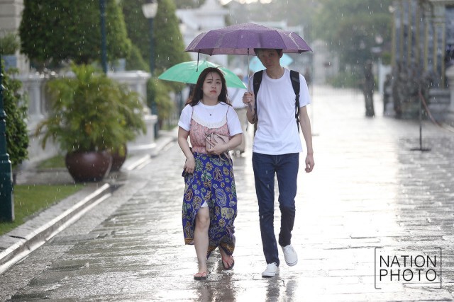 สายฝนโปรยปรายทั่วกทม.
นทท.ยืนกางร่มหลบฝนที่วัดพระแก้ว