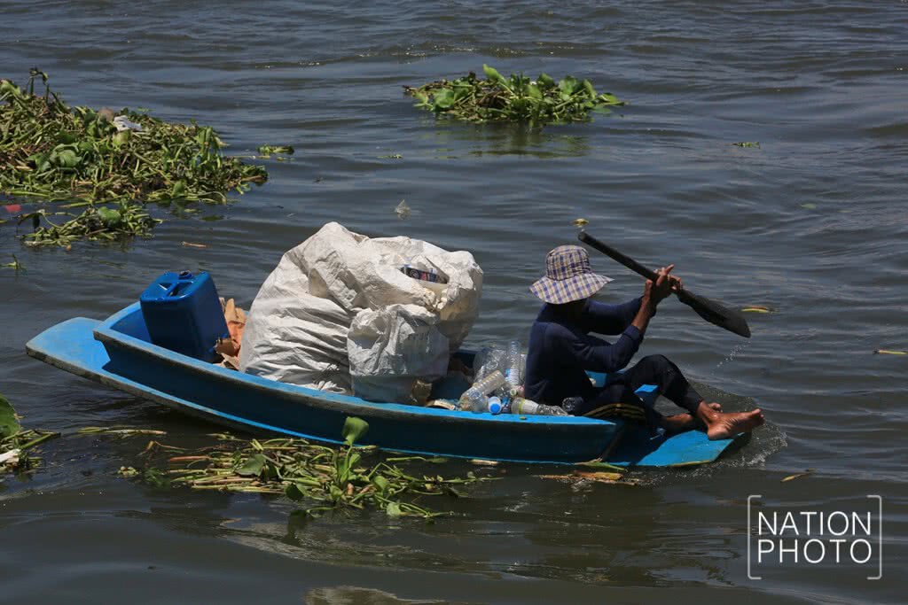ชาวบ้านพายเรือเก็บขวดน้ำพลาสติกที่ลอยเกลื่อนในแม่น้ำ ชาวบ้านพายเรือเก็บขวดน้ำพลาสติกที่ลอยเกลื่อนในแม่น้ำ