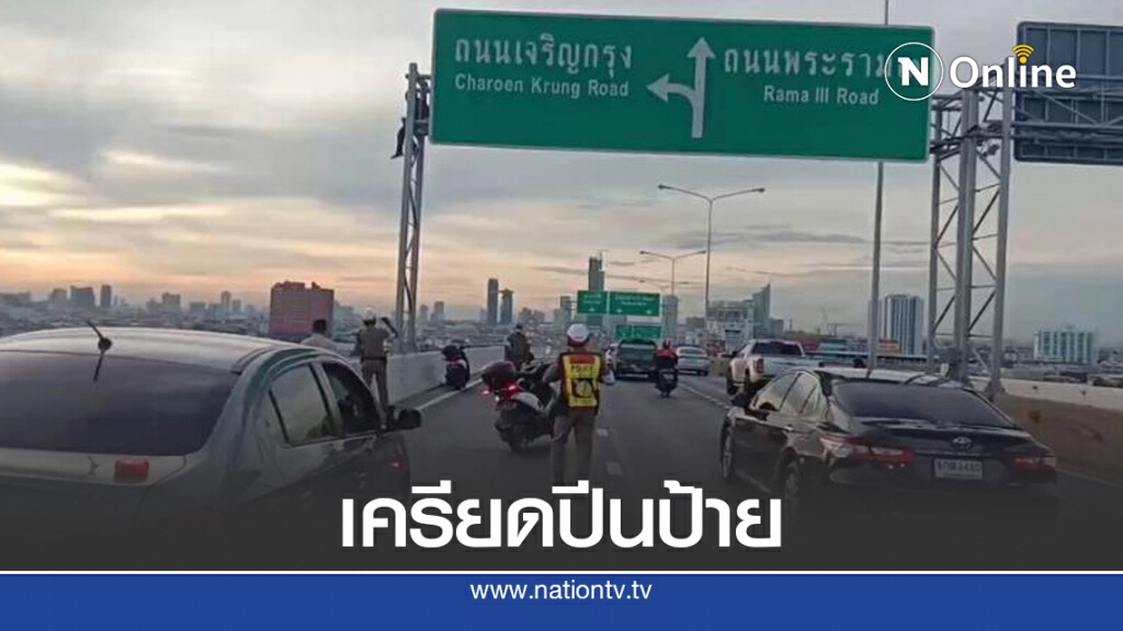ชาวบ้านโวย หนุ่มปีนป้ายกลางสะพาน ทำรถติดหนึบ