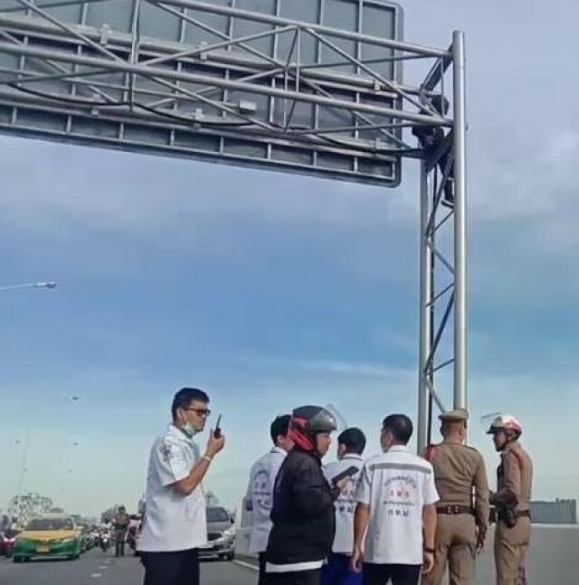 ชาวบ้านโวย หนุ่มปีนป้ายกลางสะพาน ทำรถติดหนึบ