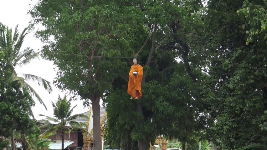 ฮือฮา หุ่นพระสงฆ์ลอยลงมาจากต้นไม้รับบิณฑบาตจีวรปลิว