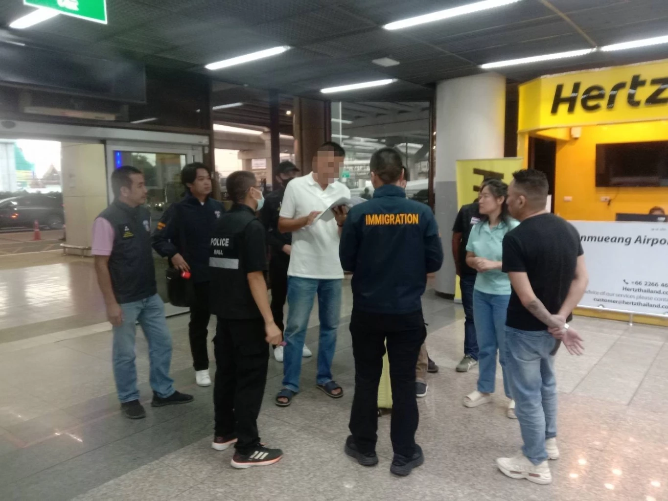 นายเว่ย ลินวู ผู้ต้องหาตามหมายจับ (เสื้อดำขวาสุด)