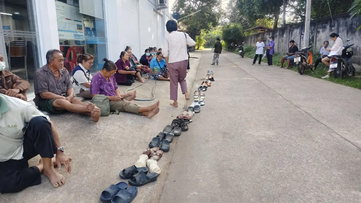 ประชาชนในต่างจังหวัดนำรองเท้ามาต่อคิวเพื่อรอยืนยันตัวตนเข้าร่วมโครงการ "คนละครึ่งพลัส"